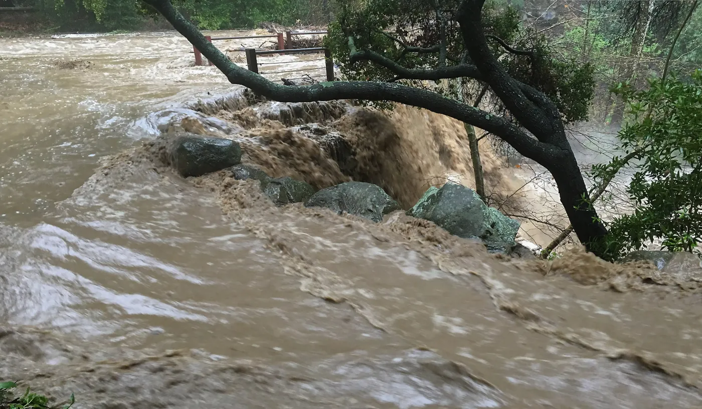 Water flowing around west end of Mission Dam during rainstorm