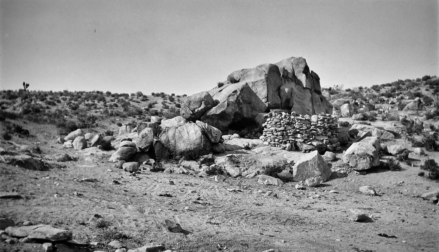 Black and white photograph of a manmade rock formation on top of a large flat rock.