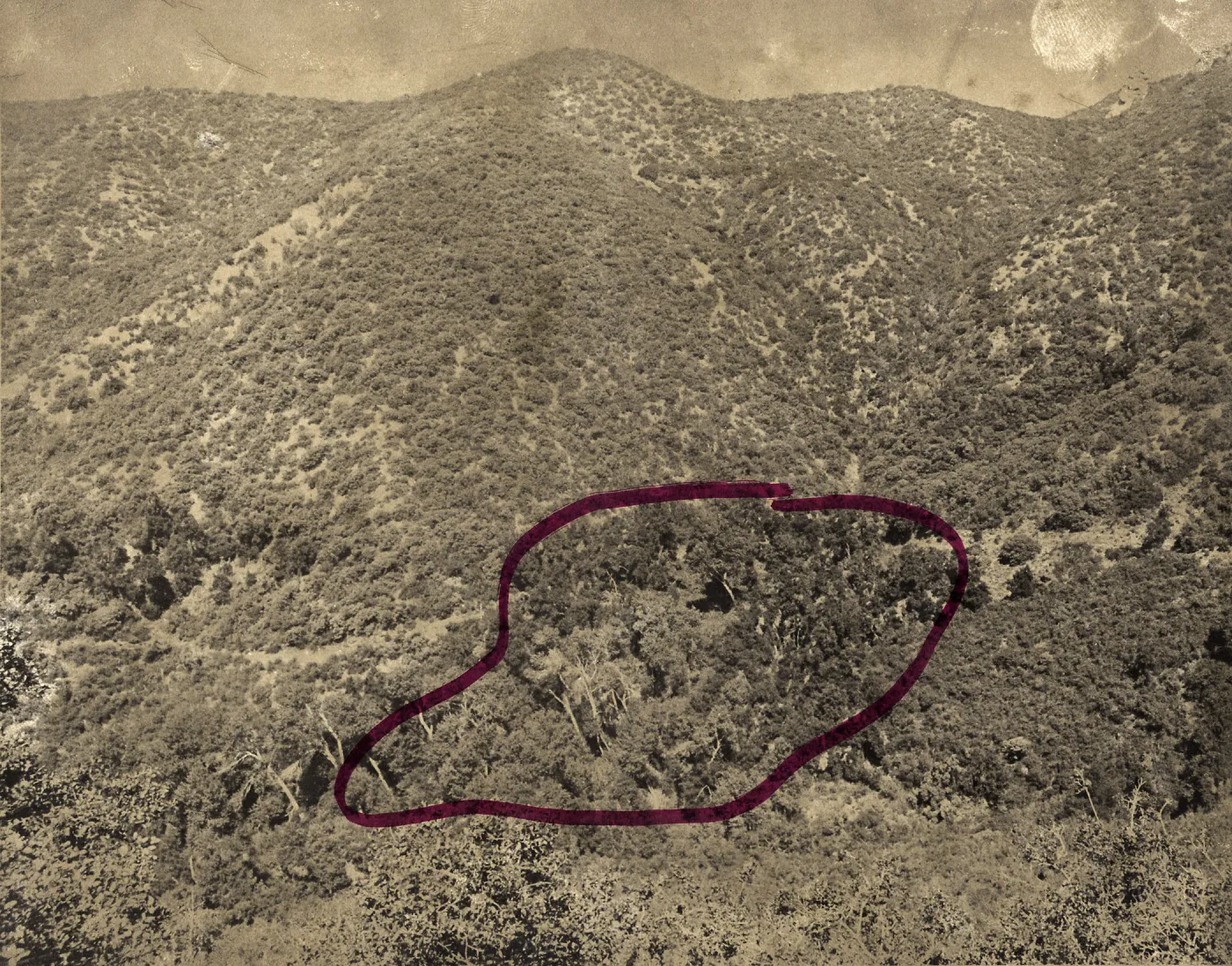 Black and white photograph of mountain with a section in the middle circled in red. 