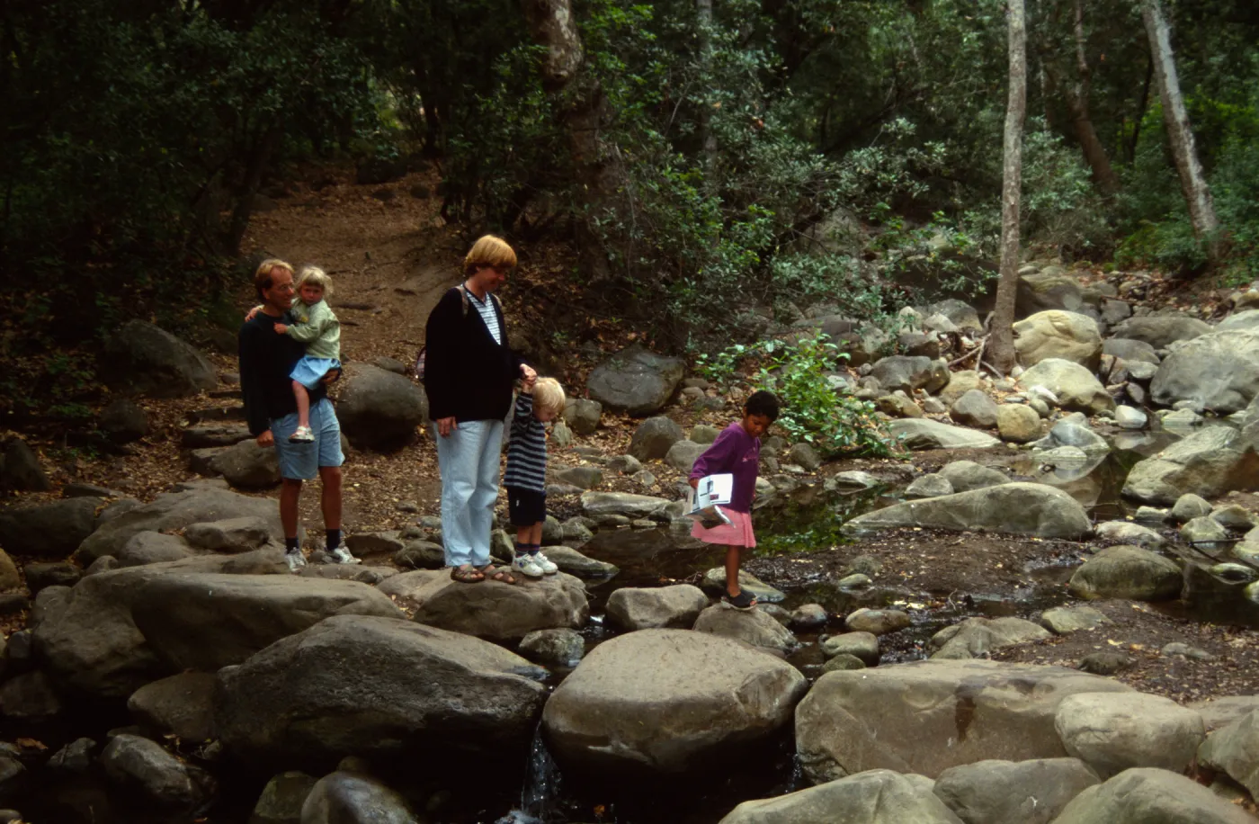 family crossing Mission Creek on boulders at creek crossing