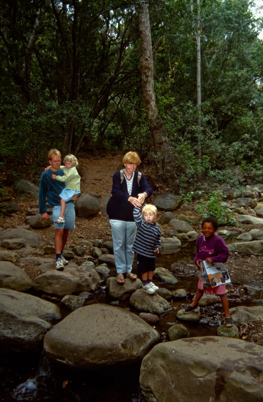 family crossing Mission Creek on boulders at creek crossing