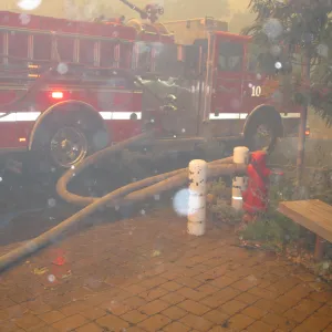Fire truck with hose attached to the fire hydrant at the main entrance, during the Jesusita Fire