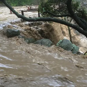 Water flowing around west end of Mission Dam during rainstorm