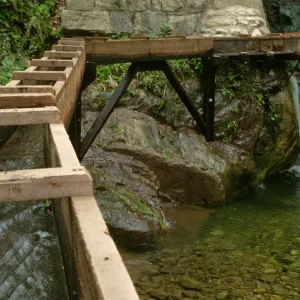 wooden aqueduct with flowing water and waterfall under Mission Dam